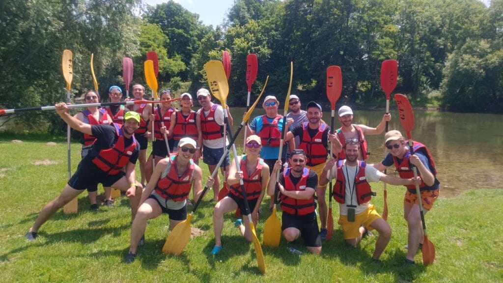 Groupe Atousports en gilets et pagaies au bord de l’eau, pendant le stage multisport