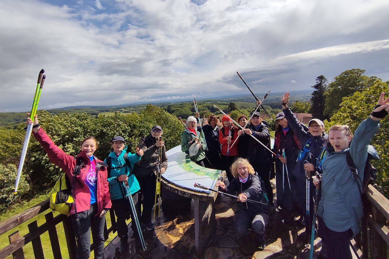 Groupe de marcheurs, bâtons levés, autour d’une table d’orientation