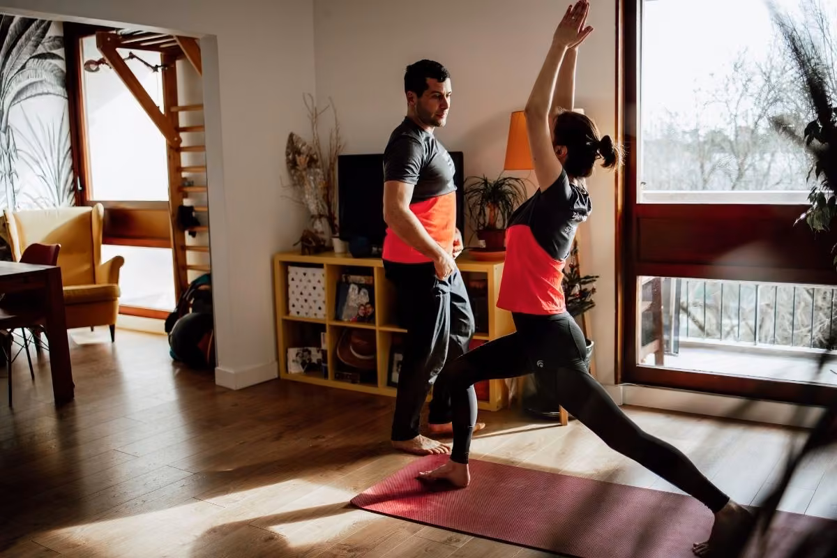 Coach sportif à domicile en Essonne : fente bras levés guidée dans le salon