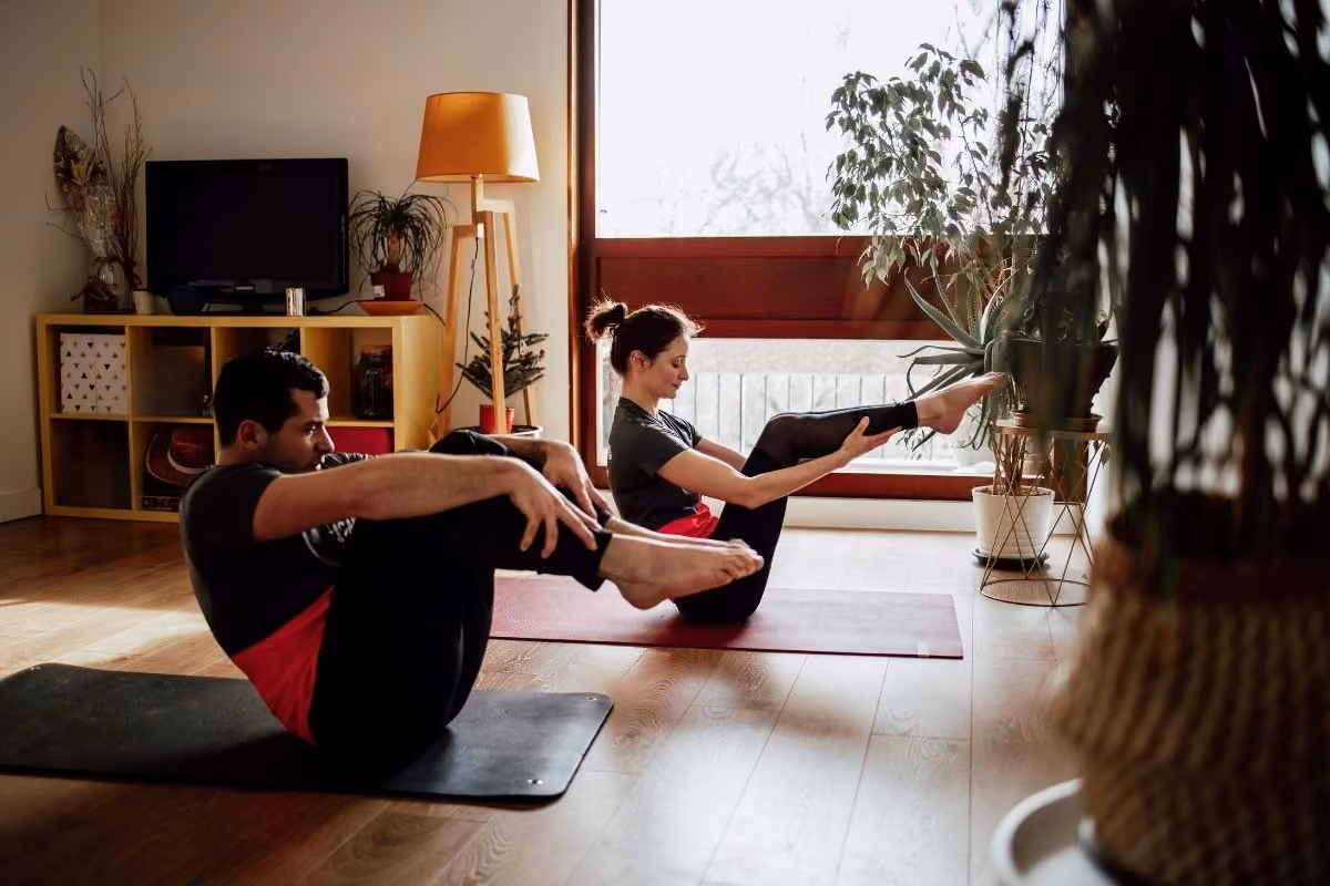 Coach et cliente assis sur tapis, jambes pliées, en séance à domicile