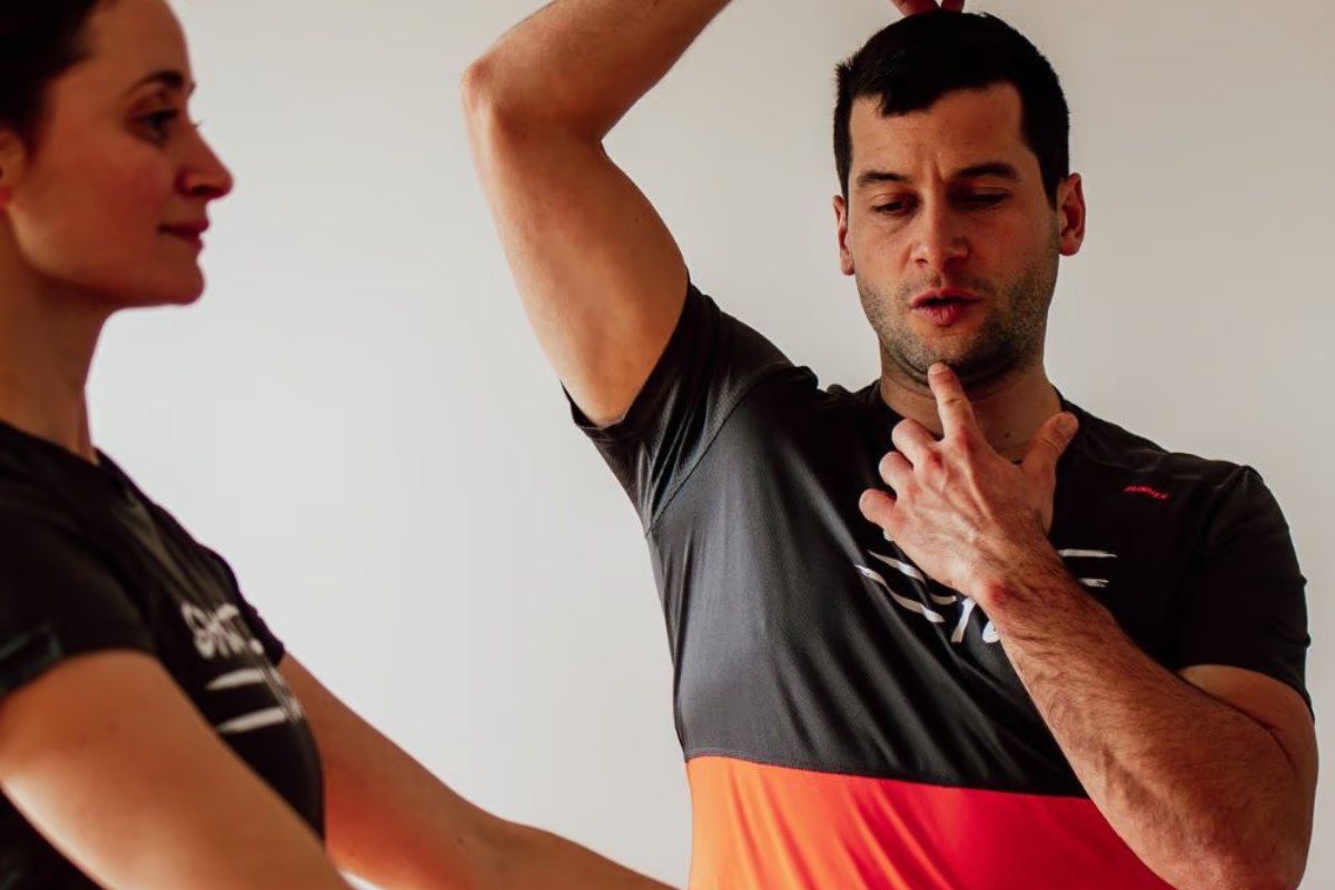 Crédit d’impôt coach sportif : séance à domicile, Kévin Richard montre un mouvement d’épaule à une cliente