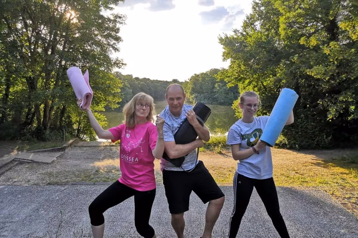 Trois participants joyeux avec leurs tapis avant une séance de coaching en extérieur