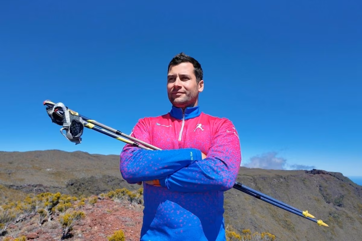 Kévin Richard, bâtons sur les épaules, devant les reliefs de La Réunion