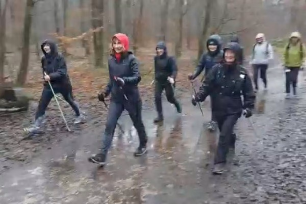 Le groupe marche sous la pluie en capuches, bâtons en main
