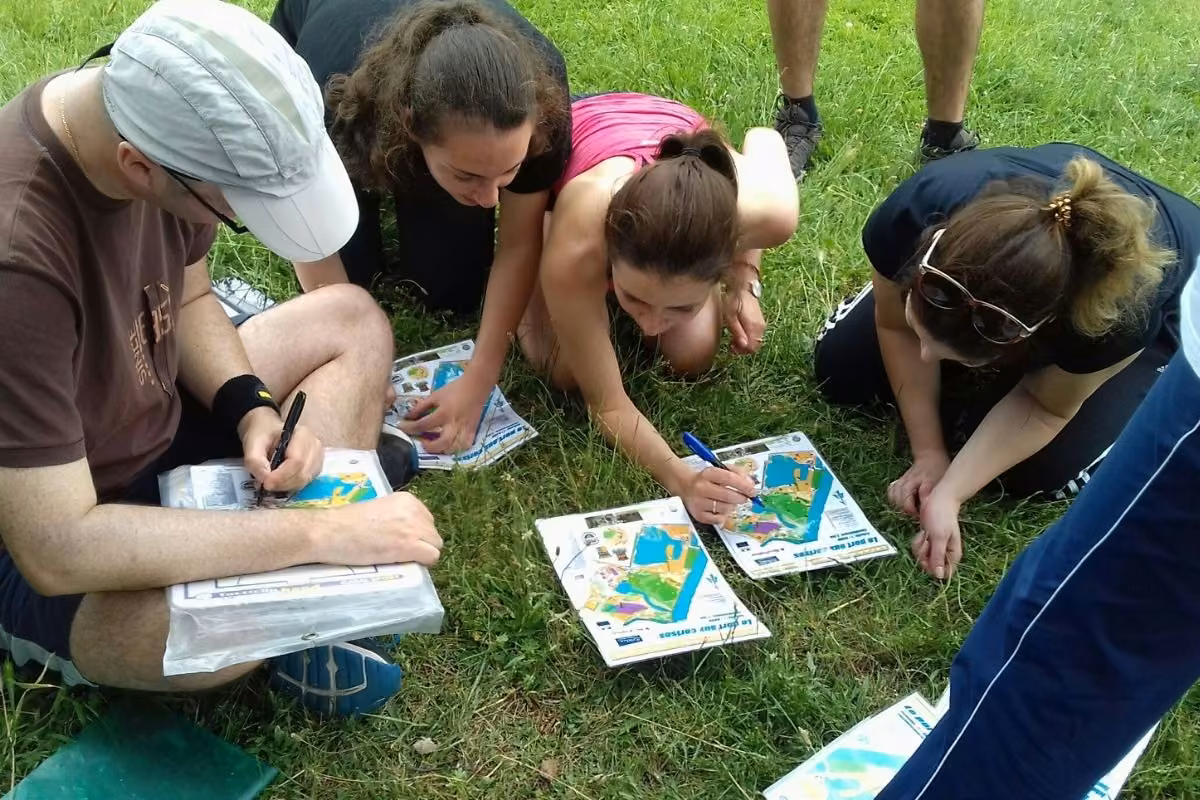 Participants penchés sur des cartes de course d'orientation dans l'herbe