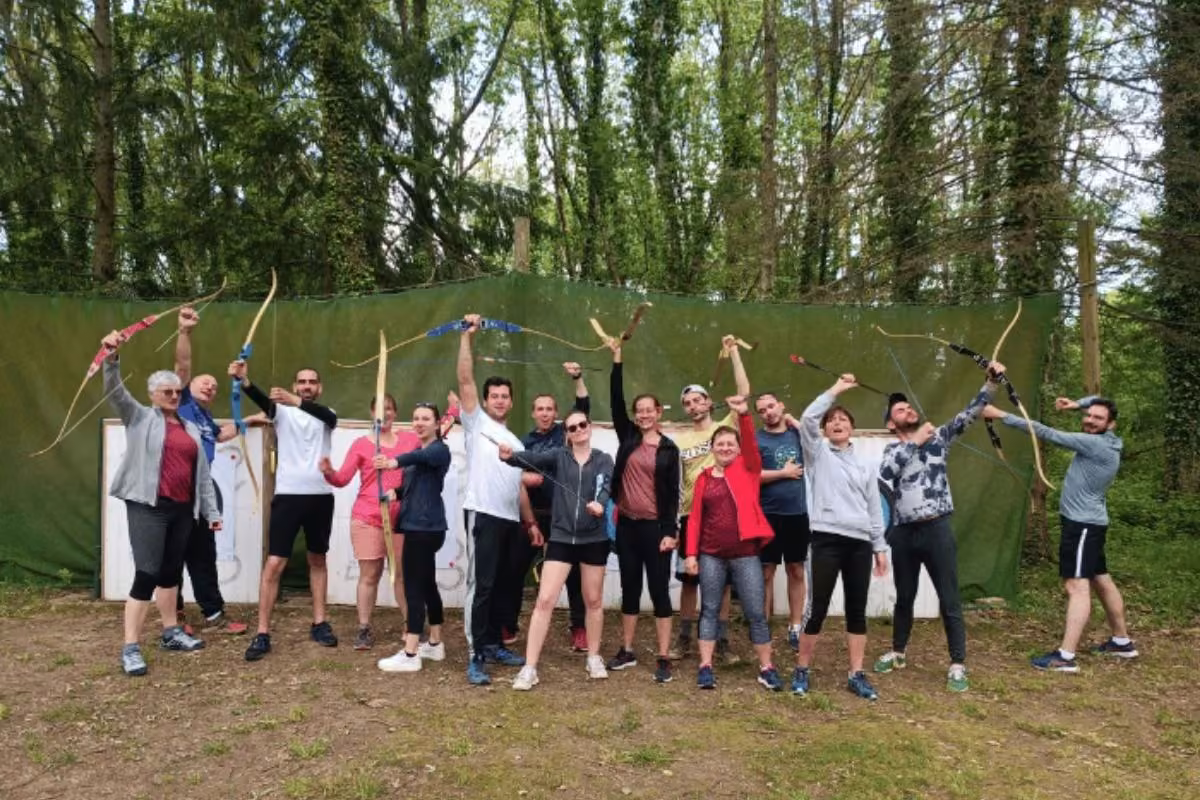 Groupe joyeux avec arcs après une initiation au tir à l'arc, multisport adultes