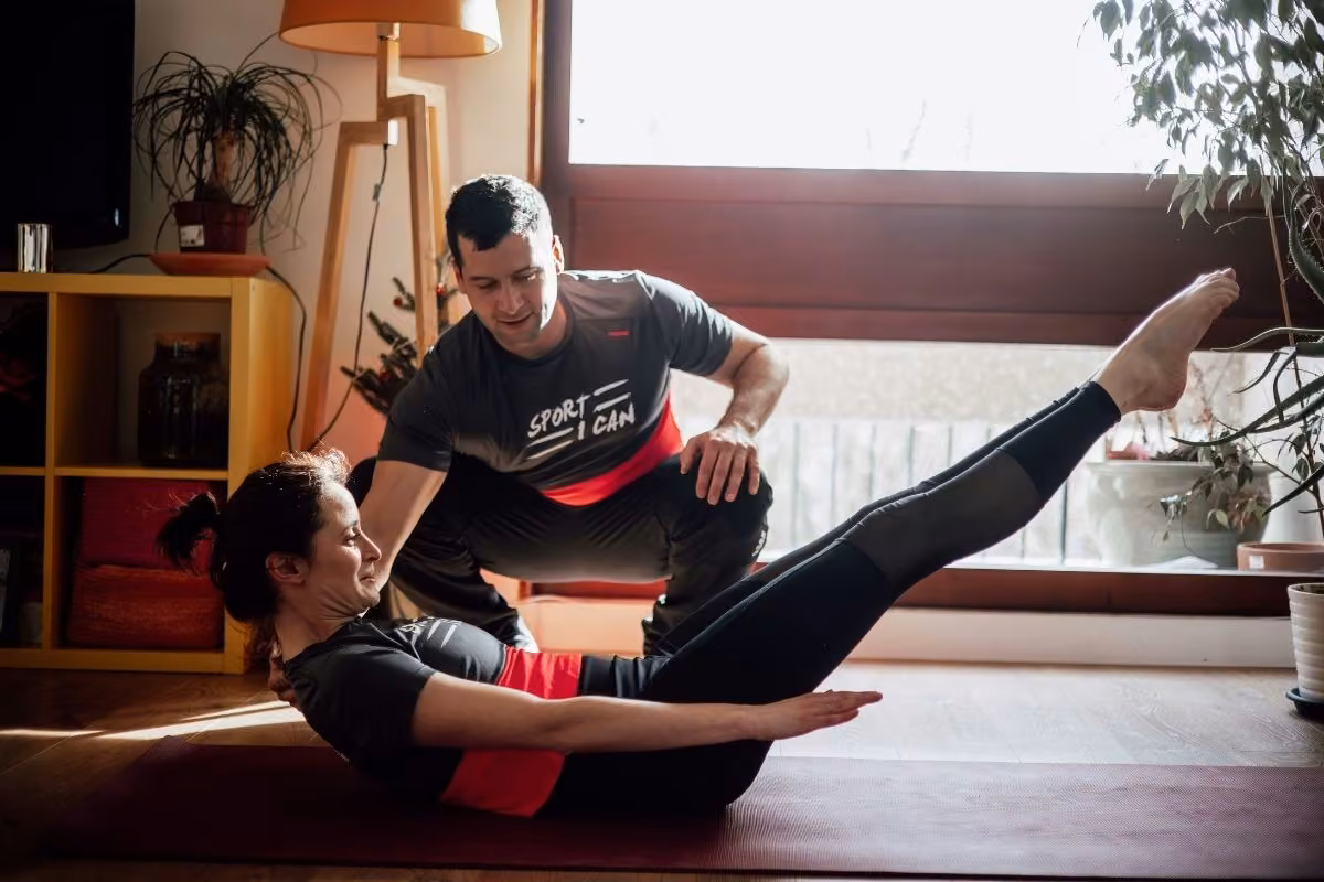 Le coach corrige une cliente en exercice d'abdominaux jambes tendues