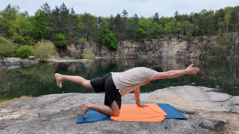 Pilates en extérieur : exercice d’équilibre à quatre pattes sur un tapis, au bord de l’eau