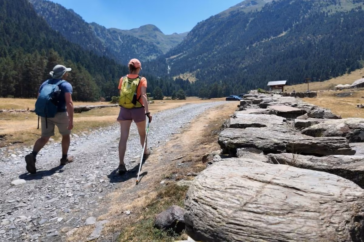 Randonneurs sur un chemin de gravier dans une vallée de montagne