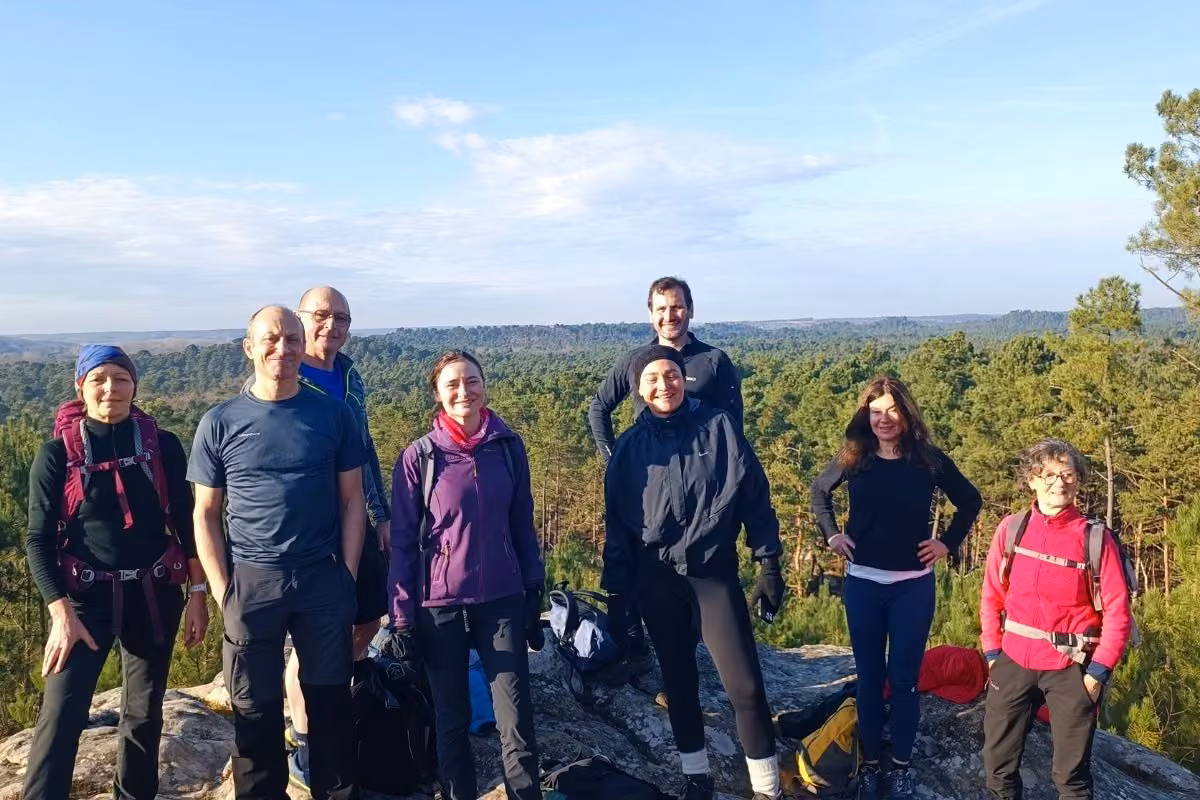 Groupe de randonneurs posant sur un sommet rocheux avec vue sur la forêt