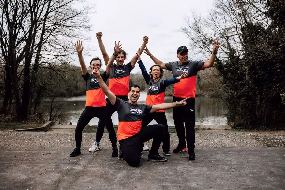 Équipe de coachs Sport, I Can, bras levés, devant un étang